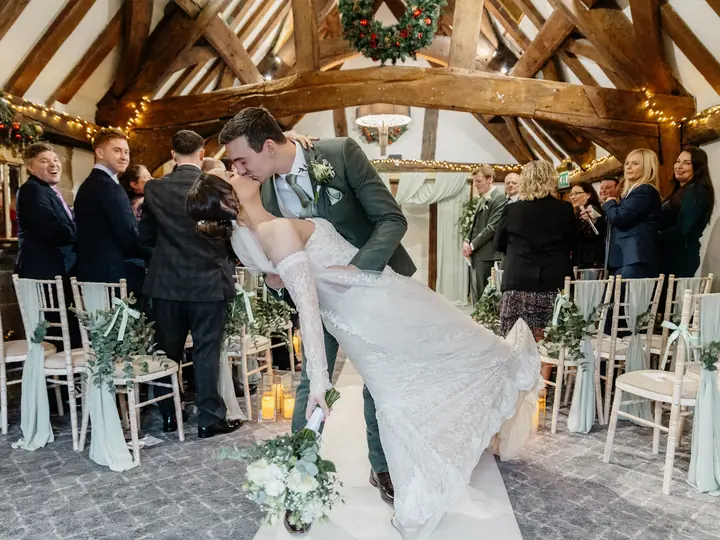 A couple sharing a kiss in the aisle of a barn ceremony