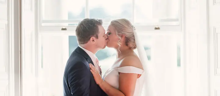 A couple kissing in front of a bright window