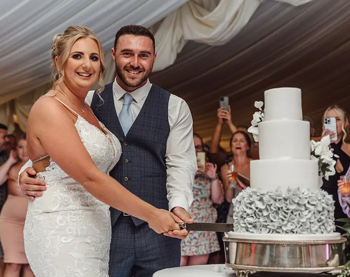 A couple cutting their wedding cake as guests watch