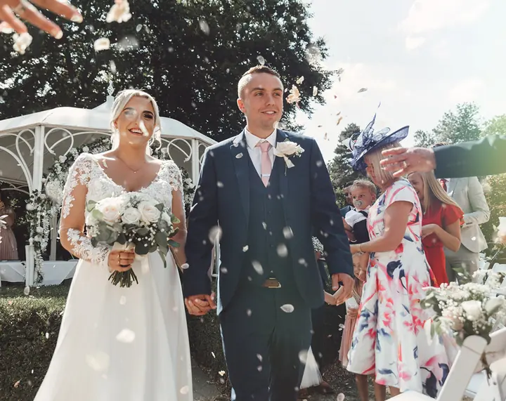 A couple walking through confetti in a garden
