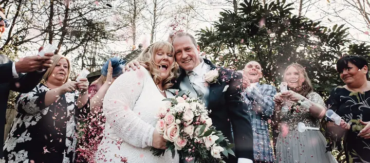 A couple laughing as confetti falls around them