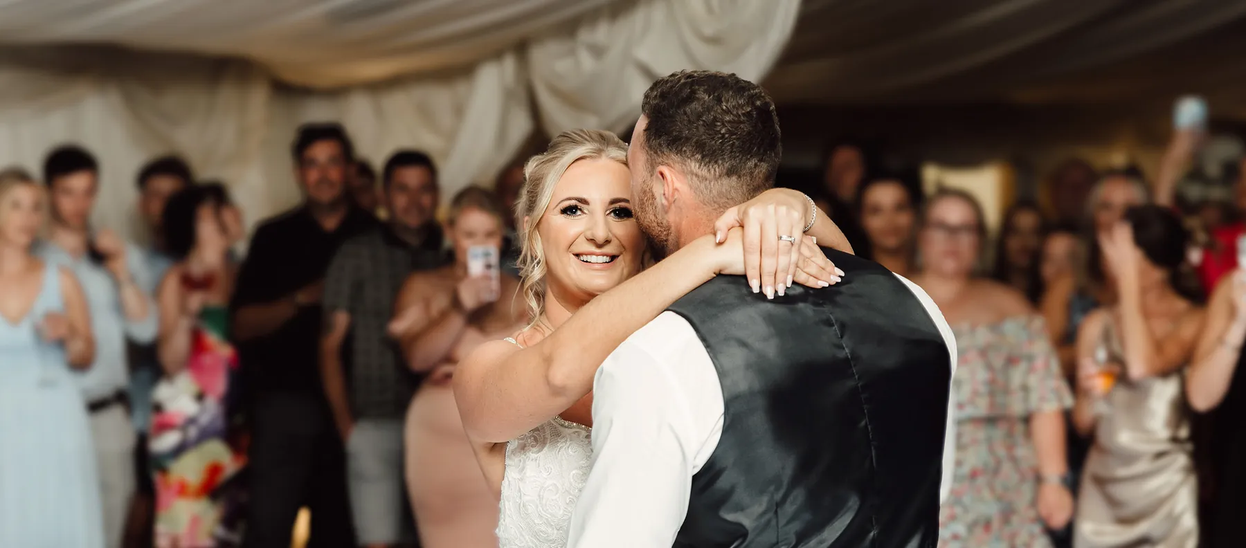 A couple embracing on the dancefloor surrounded by guests