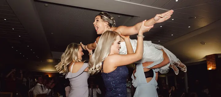 Guests lifting the bride up on the dancefloor
