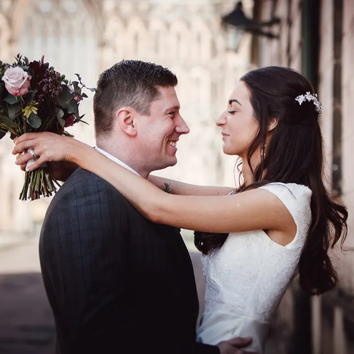 A couple embracing, the bouquet held behind his back