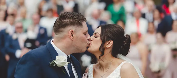 A couple kissing in front of their guests