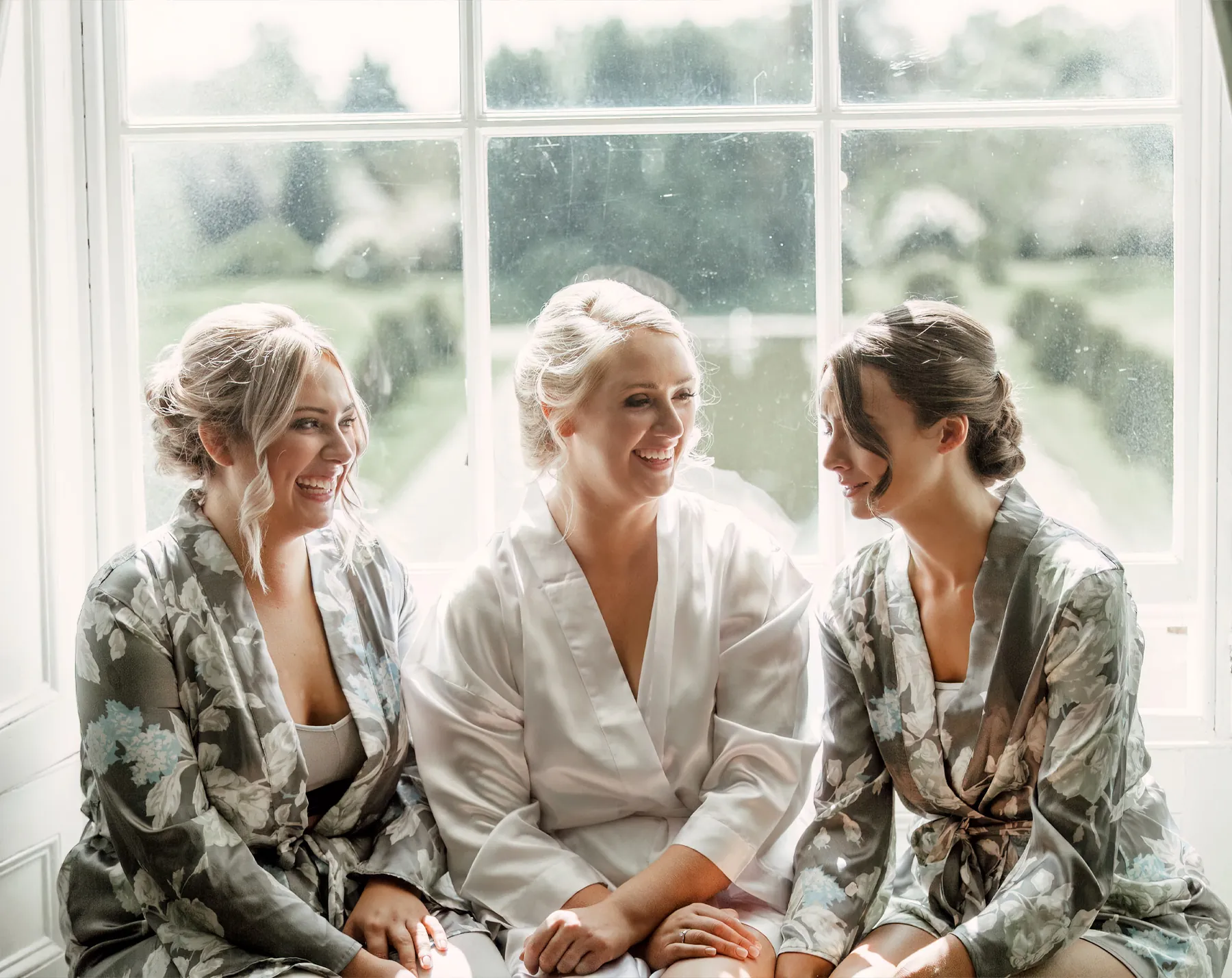 A bride and her bridesmaids laughing together in matching robes