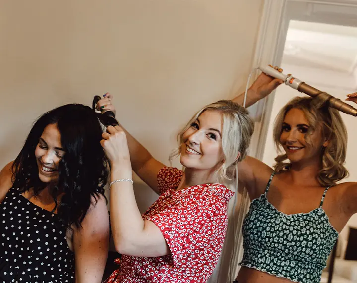 Bridesmaids laughing while their hair is being curled