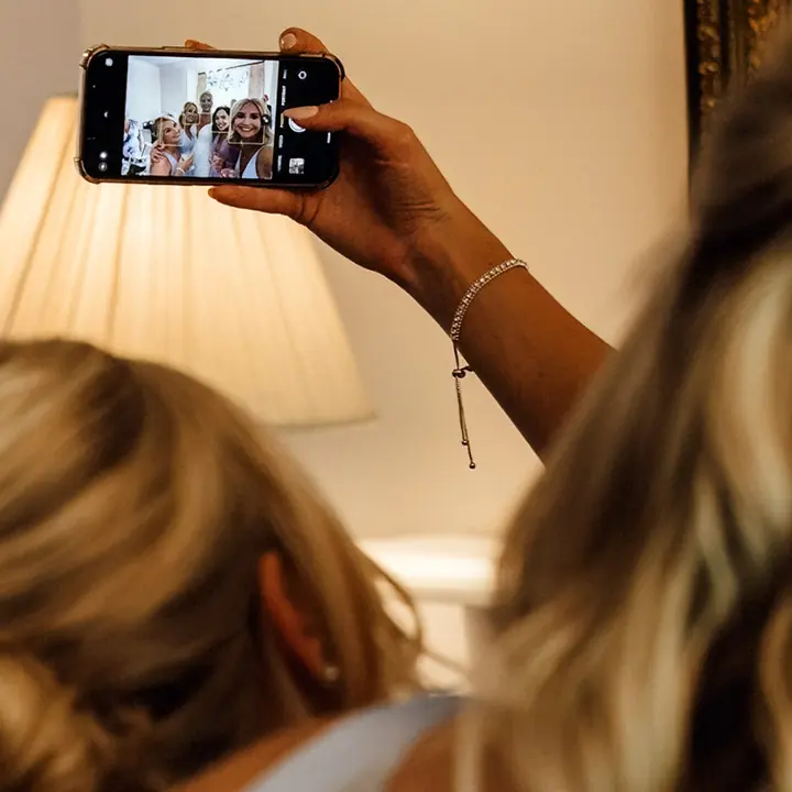 A bridesmaid taking a selfie on her phone while getting ready