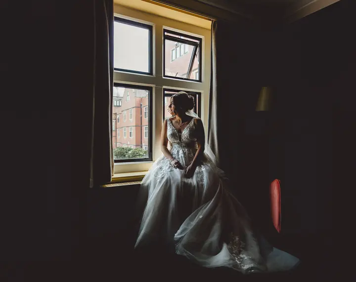 A bride sitting quietly by a window before the ceremony