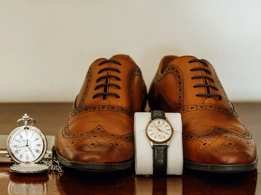 Groom's brogues, wristwatch and pocket watch laid out