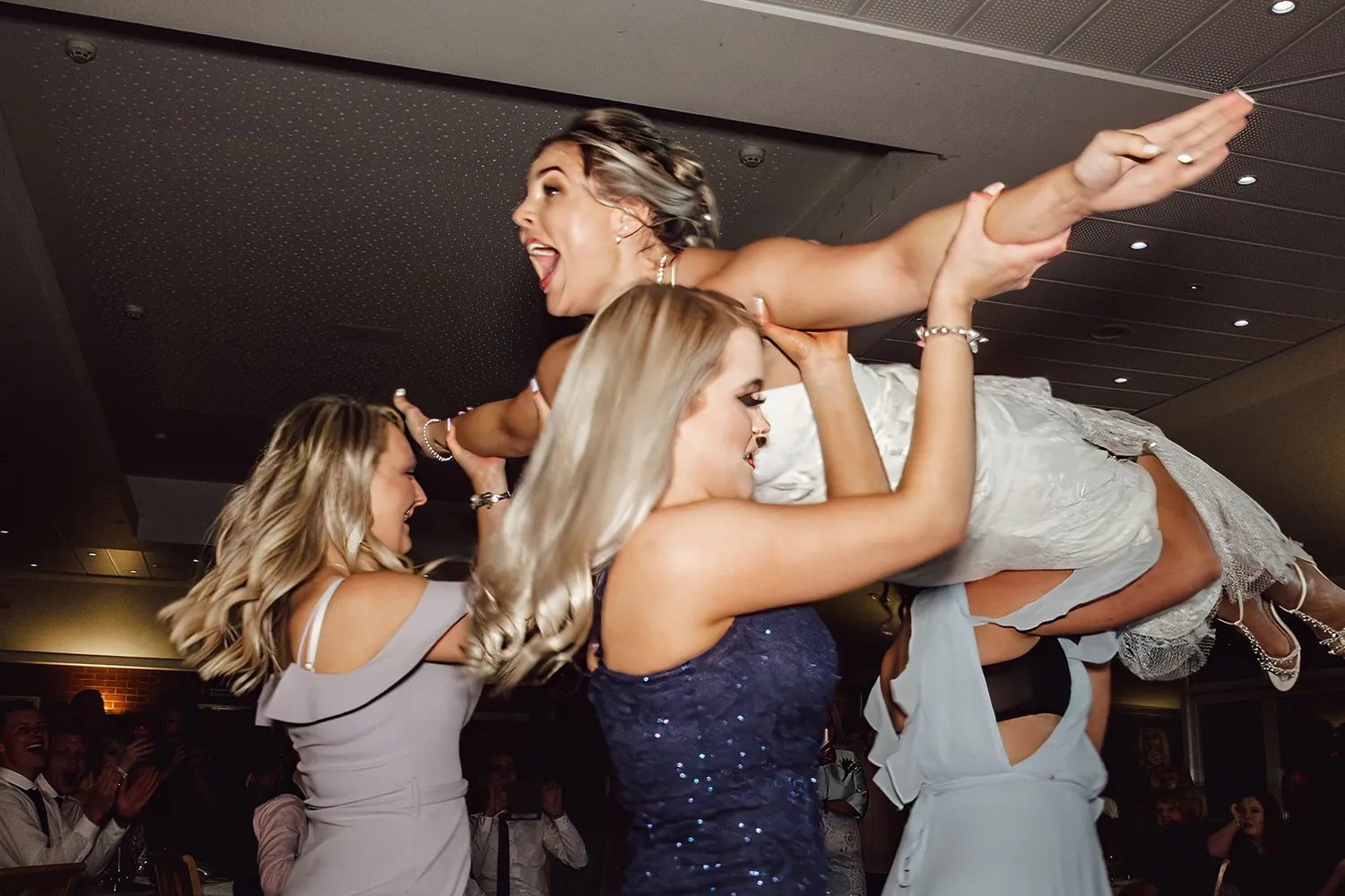 Bridesmaids lifting the bride into the air on the dancefloor