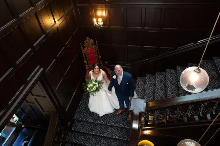 A bride and her dad walking down the grand staircase at Hoar Cross Hall