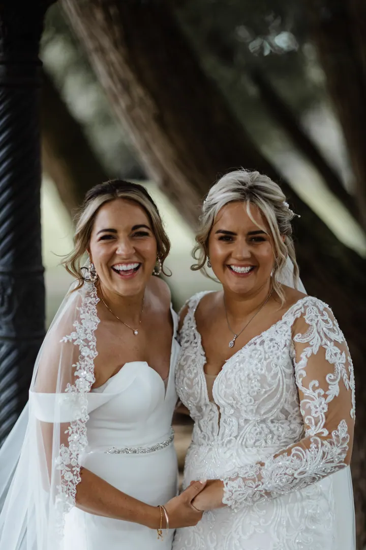 Ellisha and Miriam smiling together beneath a tree at The West Mill