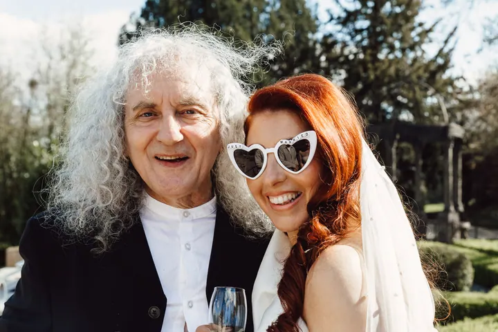 A bride in heart-shaped sunglasses laughing with a guest at Weston Hall