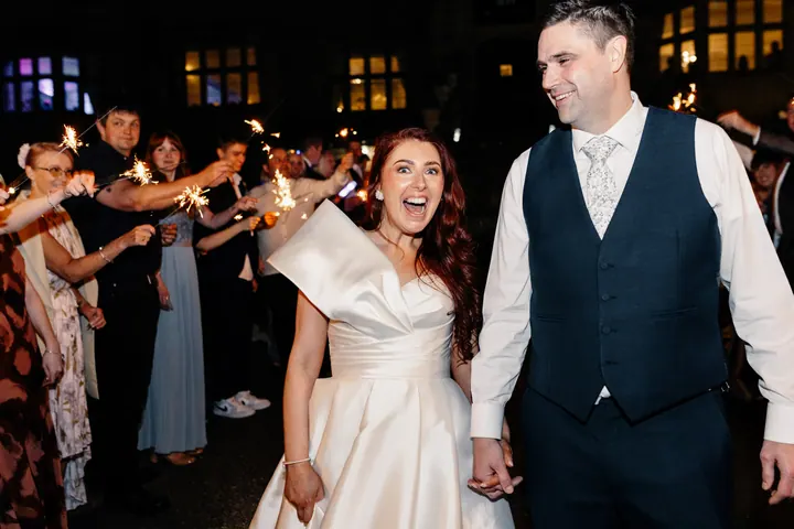 A couple laughing through a sparkler tunnel at Weston Hall